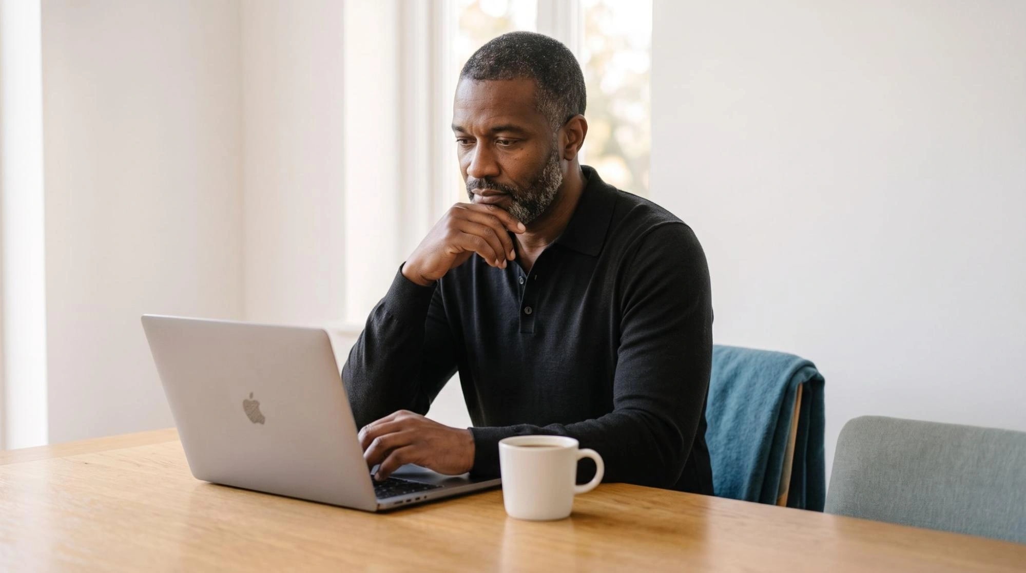 Man researching weight-loss medication options on a laptop at his kitchen table