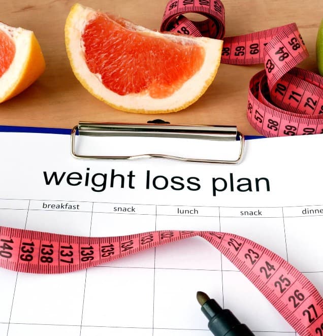 Woman looking at herself in mirror during weight loss journey