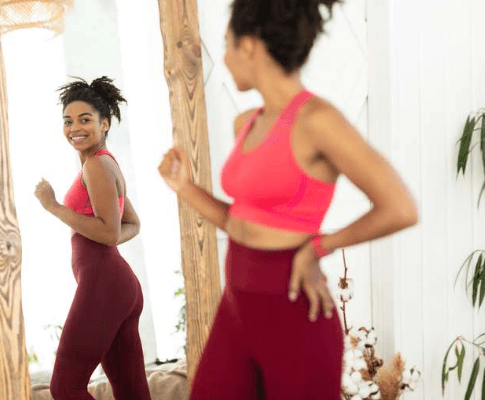 Woman looking at herself in mirror during weight loss journey