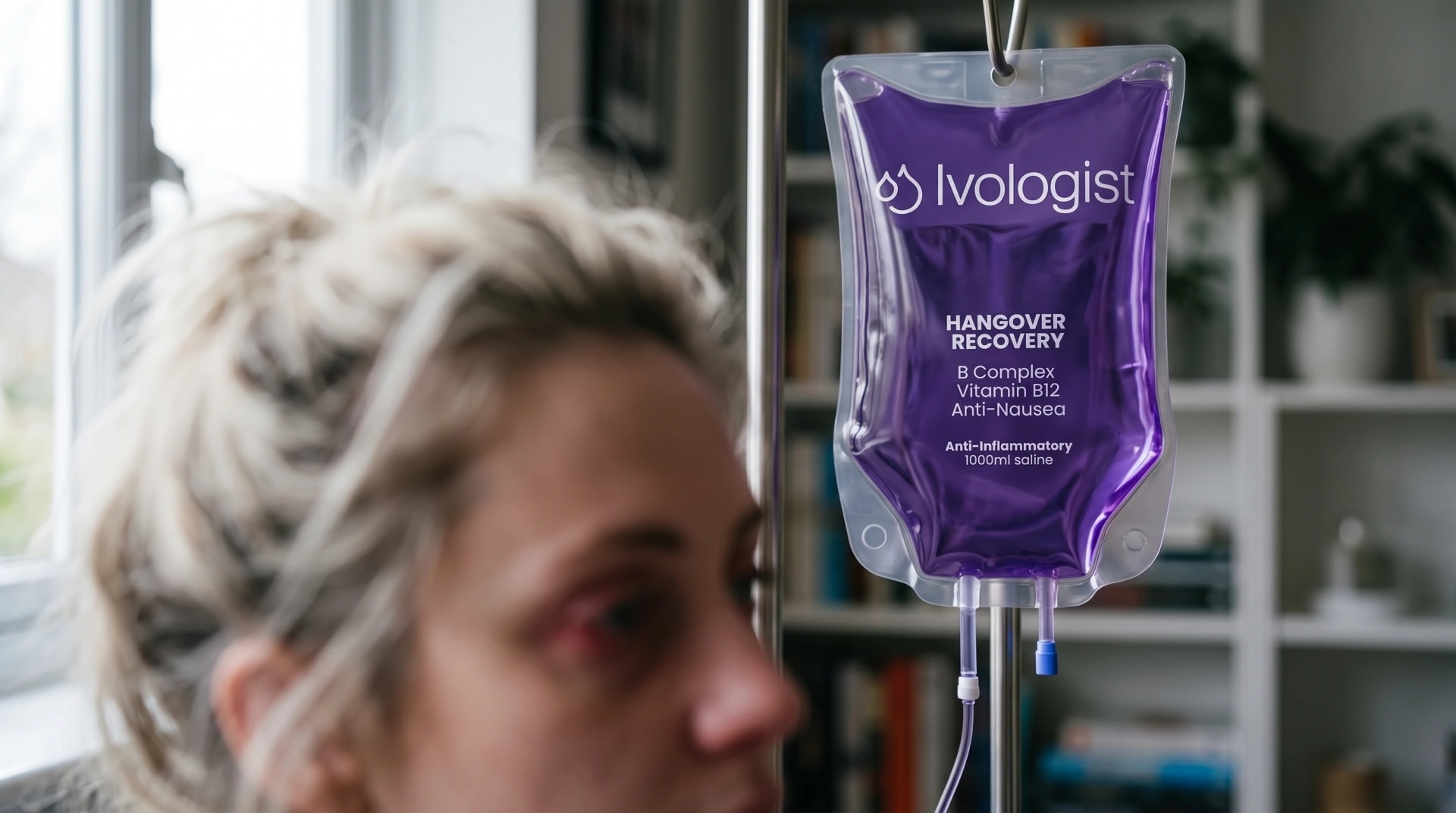 An Ivologist hangover recovery IV bag hanging on a stand, with a tired woman out of focus in the foreground