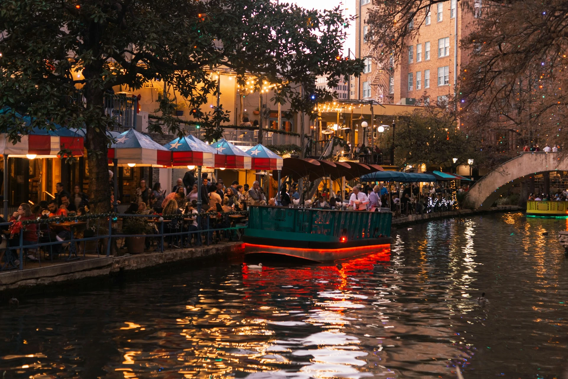San Antonio River Walk with river boats and waterside restaurants, shown at dusk