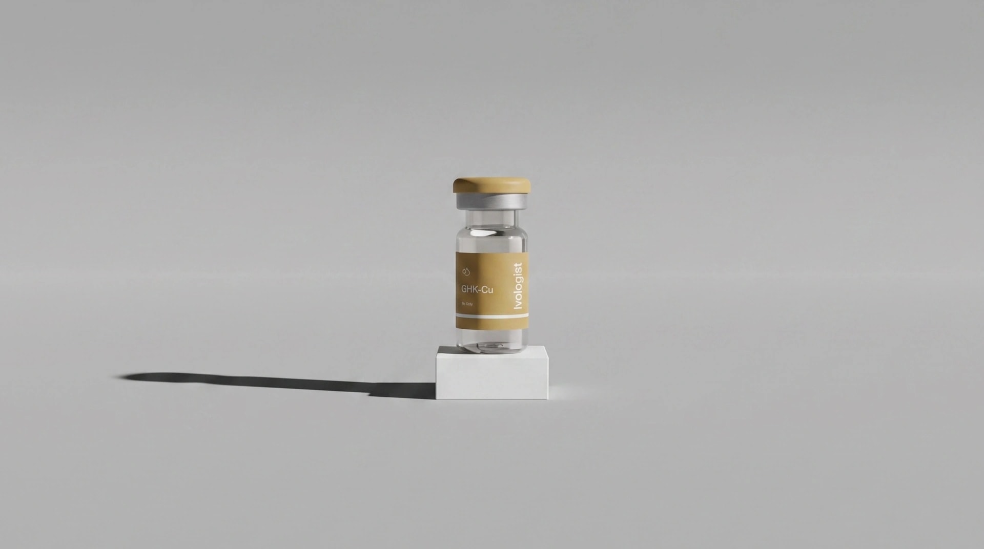 A GHK-Cu vial with a gold label standing on a small white block
