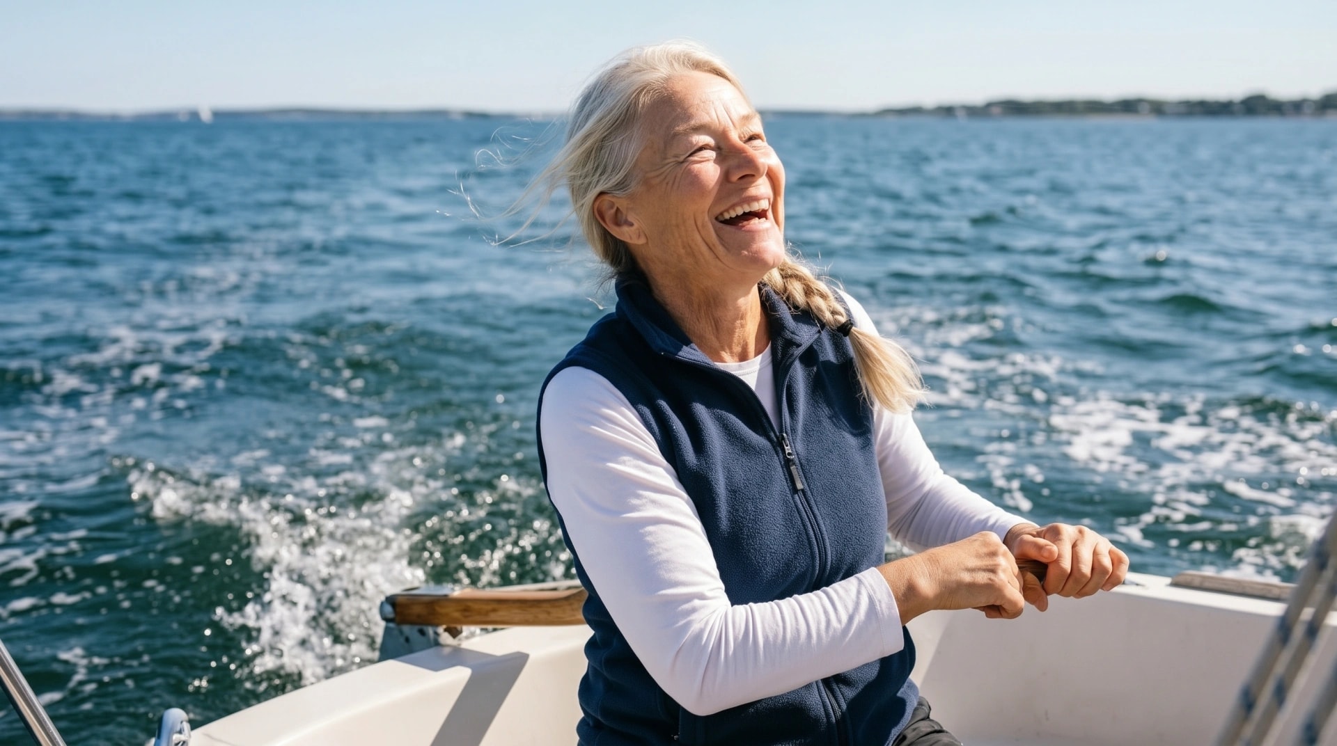 A woman laughing as she sails on open water