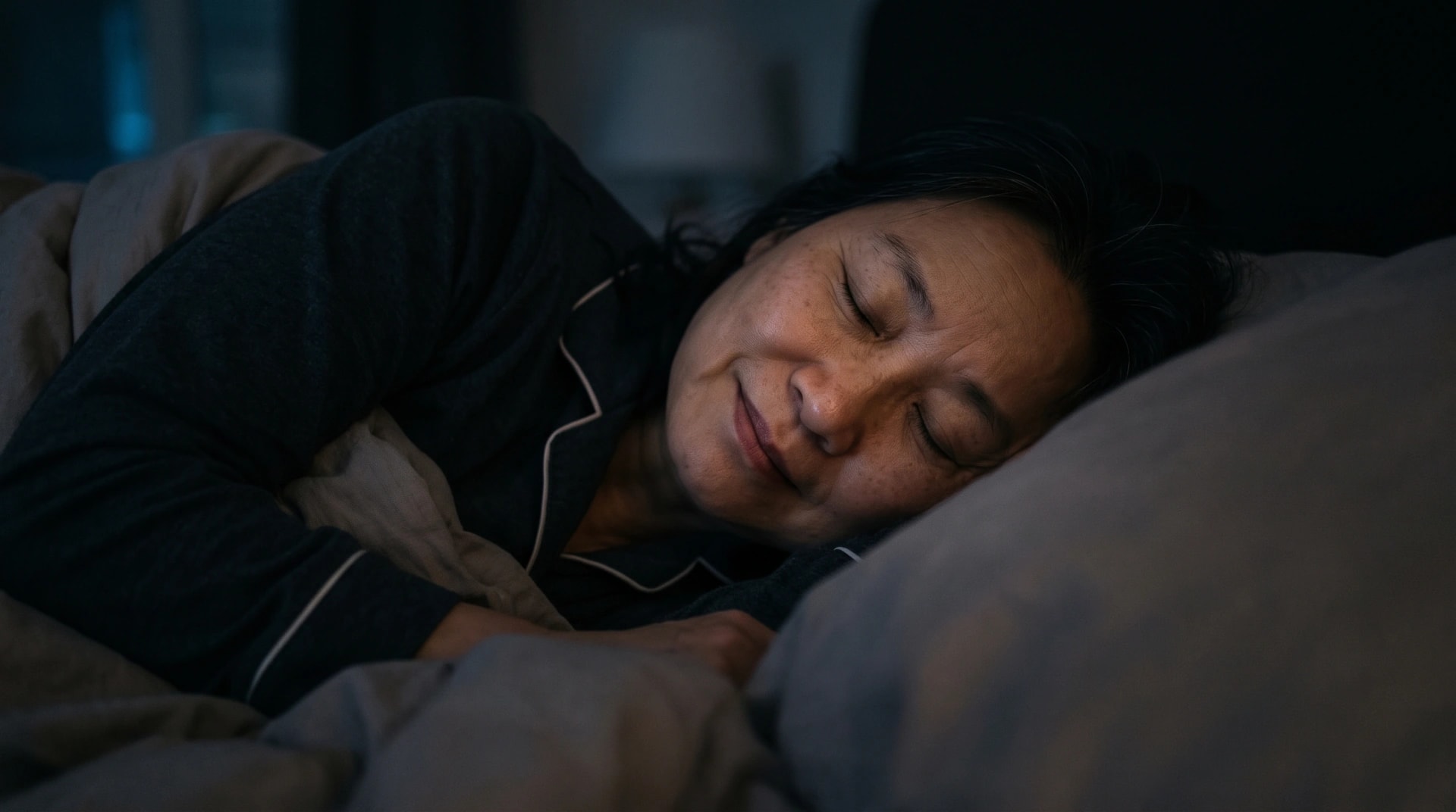 A woman sleeping restlessly in a dark bedroom
