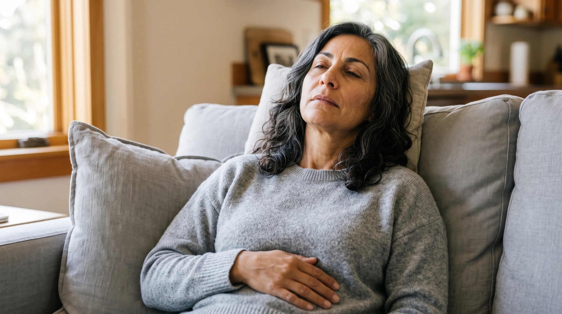 A woman resting on a sofa with a hand on her stomach